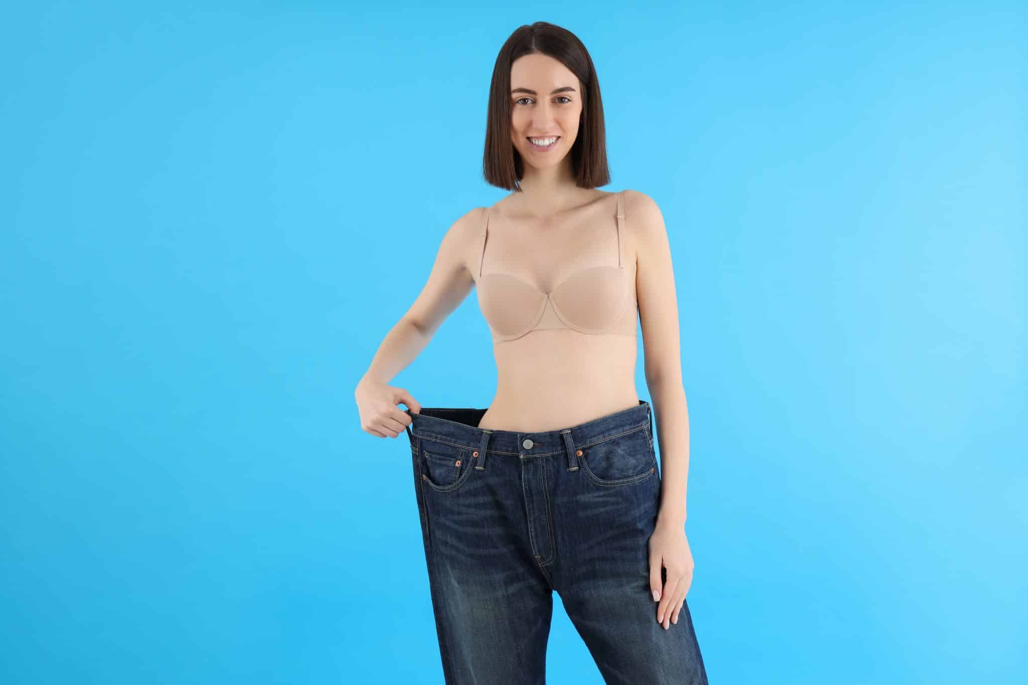 woman holding out the waist band of large pants to indicate weight loss