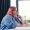 A plus size businesswoman with pink hair, wearing a blue shirt, sits at a desk looking thoughtfully off to the side.